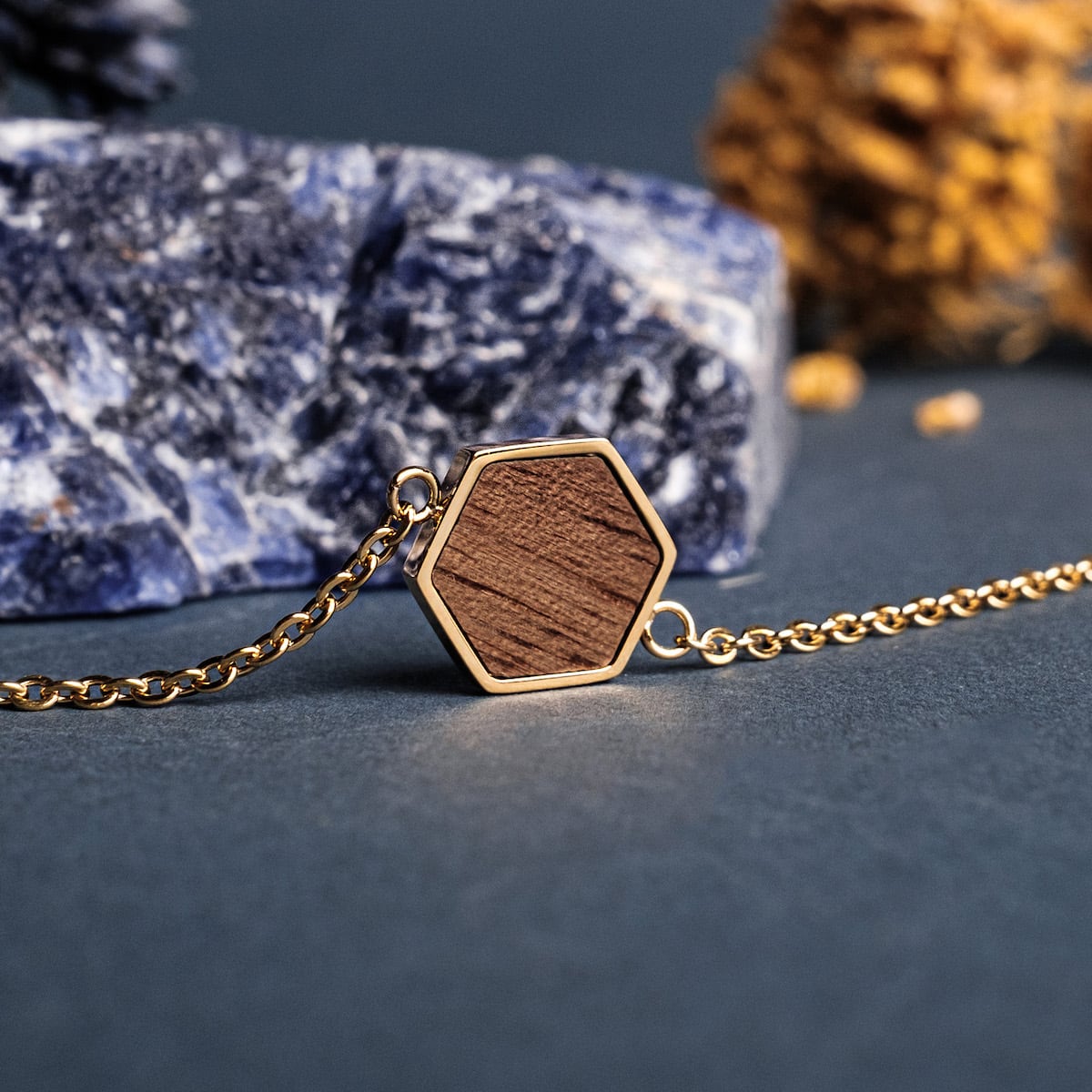 "Facade Bracelet" features a striking geometric design with walnut wood set in gold, creating a sophisticated bracelet style.