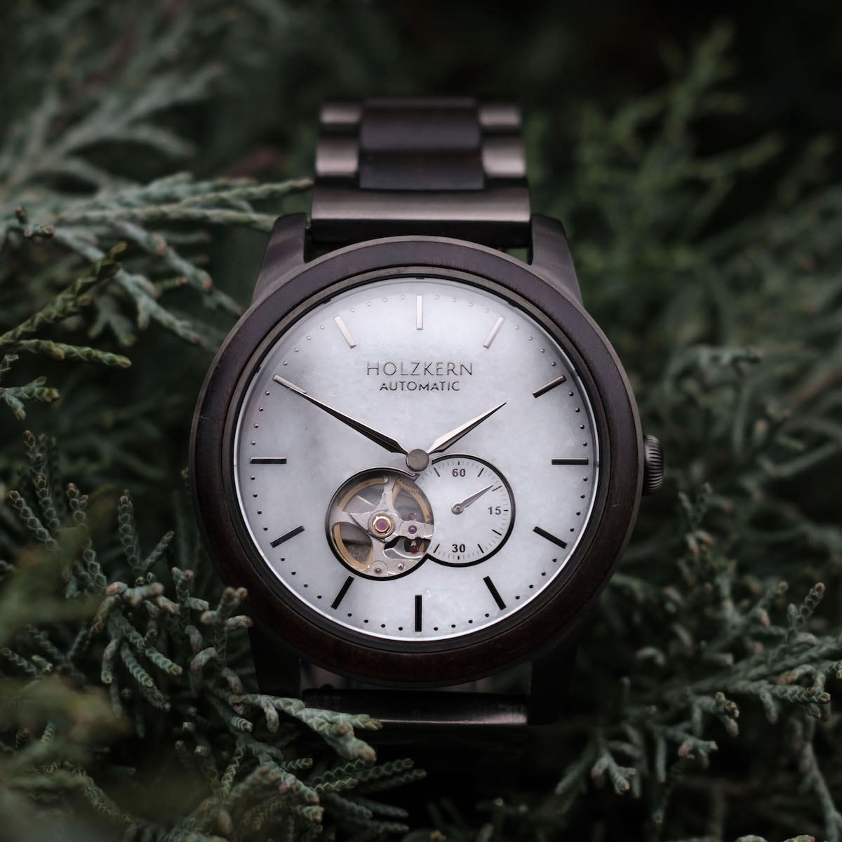 "Manhattan" watch featuring a sophisticated maple wood and marble design against a lush green backdrop.