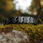 "Baritone" bracelet, sleek design in maple and dark grey, displayed on natural mossy background.