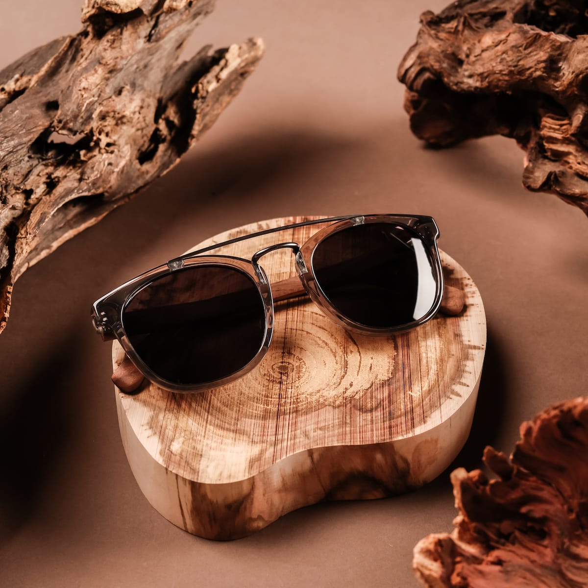 "The Trustworthy" sunglasses featuring a stylish frame with earthy Leadwood and Ash accents on a natural wood background.