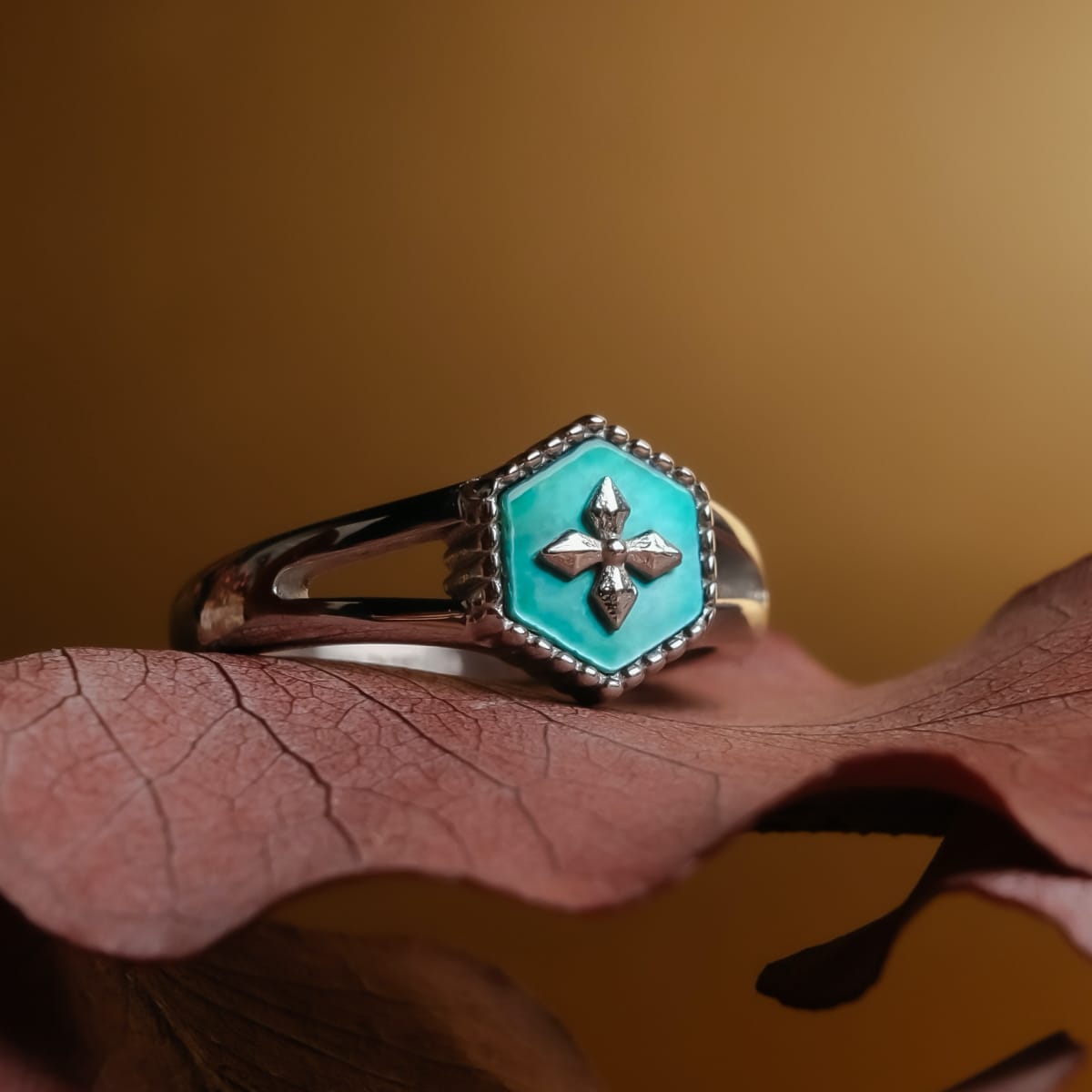 "Spectral Ring", a hexagonal silver ring with nacre accents and an intricate central design, displayed on a textured background.