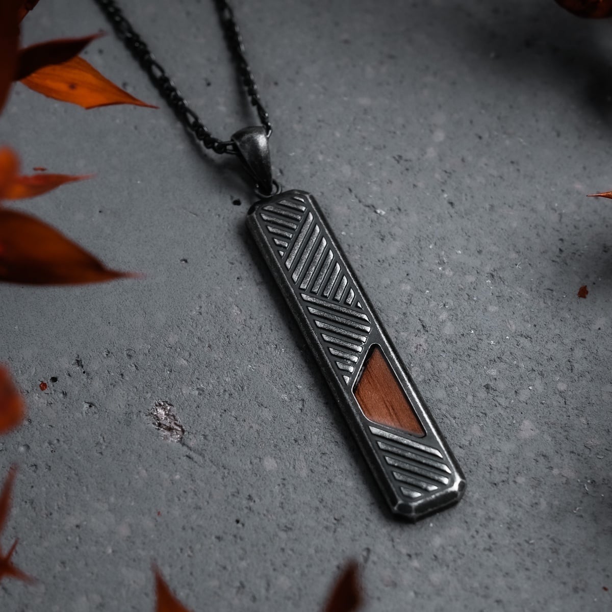 "Derivatives Necklace", a sleek necklace with a walnut inlay and antique silver finish, showcases a modern geometric design.