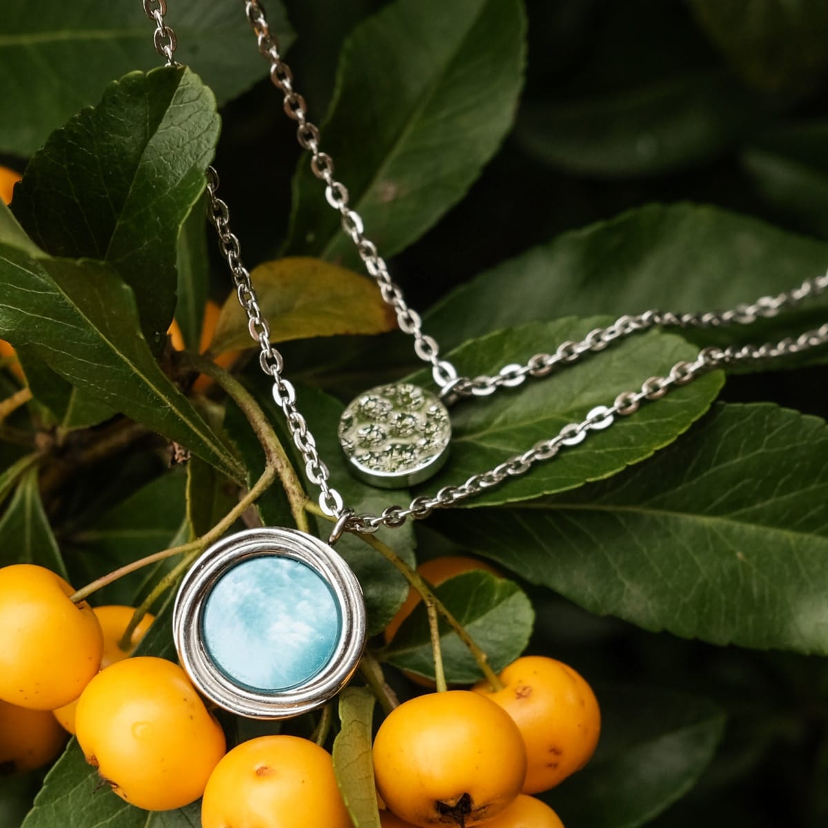 "Zendala Necklace", a stylish necklace, features a nacre and silver design with a dual pendant look.