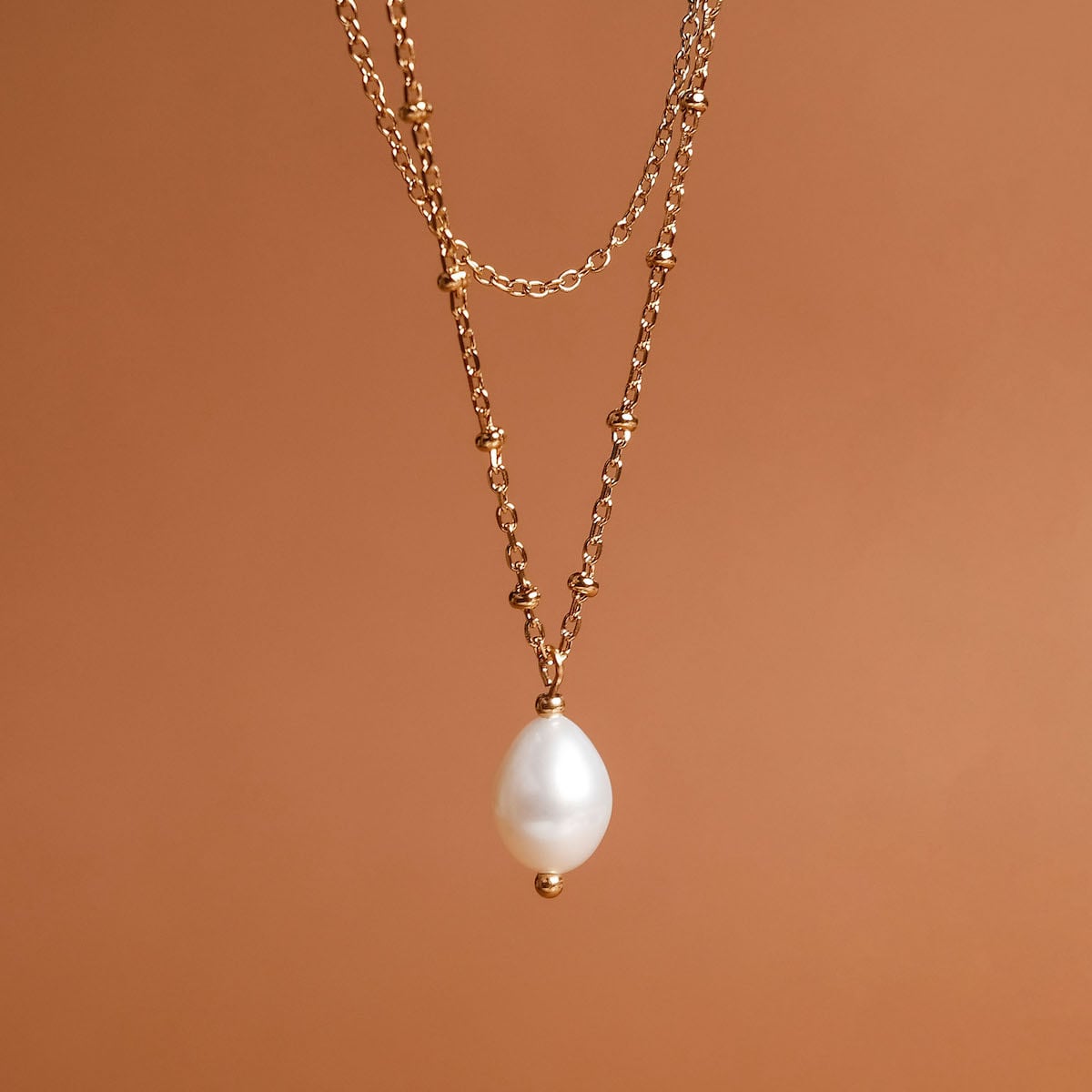 "Panoramic Necklace": elegant gold necklace featuring a white pearl pendant.