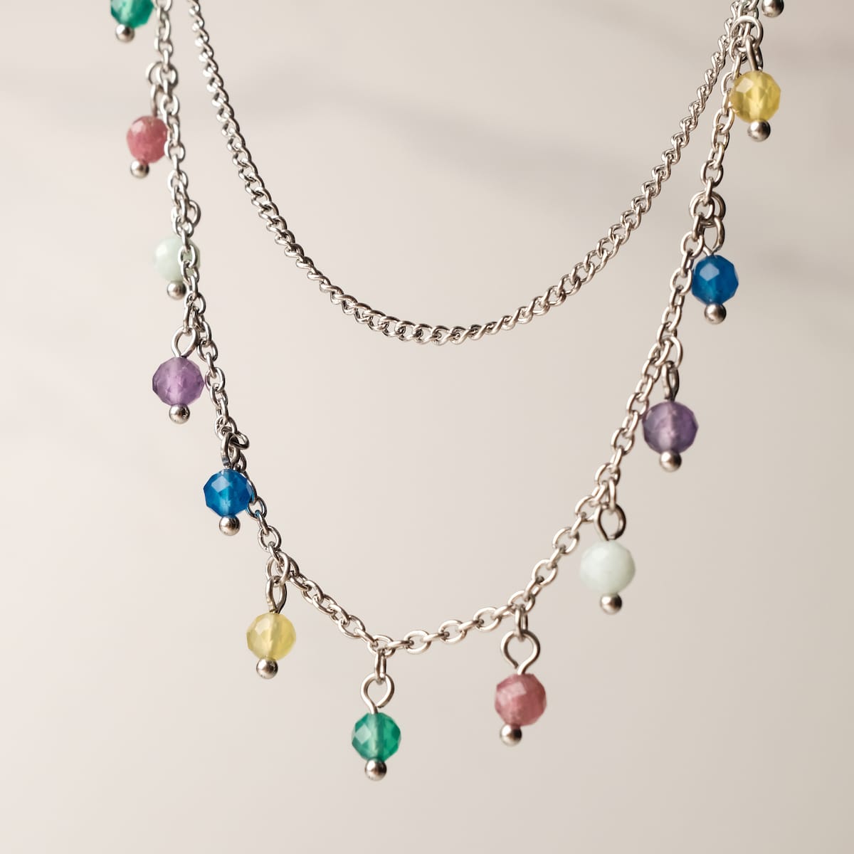 "Free Play Necklace", a vibrant necklace with rainbow beads and silver chains, offers a playful style.