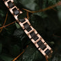 "Acoustic" bracelet in maple and rose gold, featuring a sleek, natural aesthetic among green foliage.