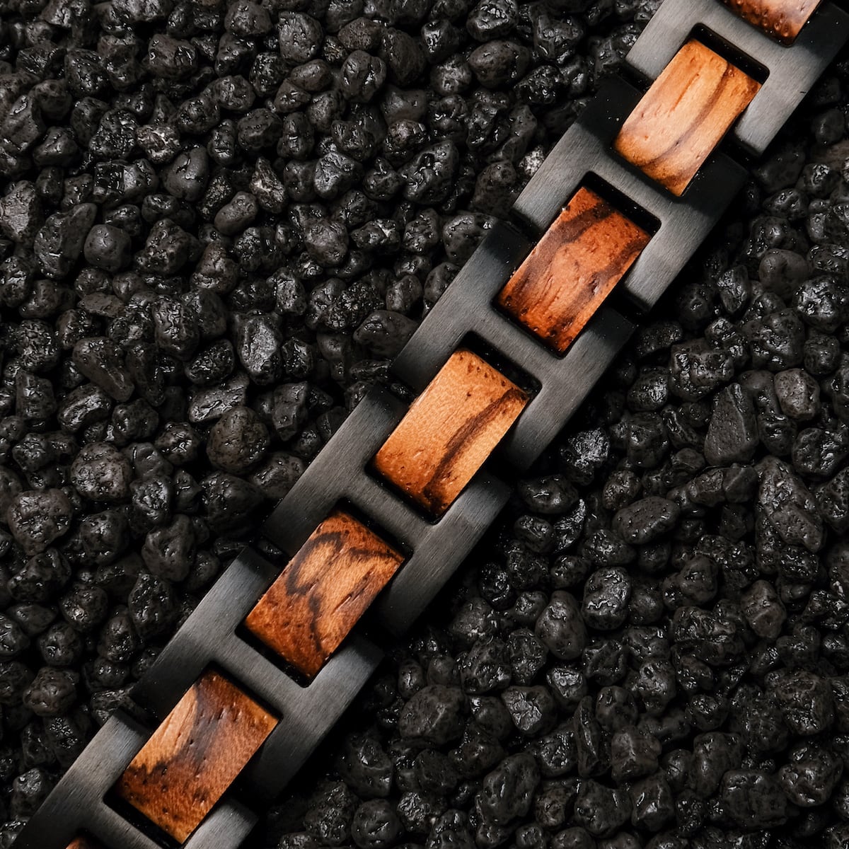 "Acoustic" watch band with zebrawood accents and black links on a textured dark background.