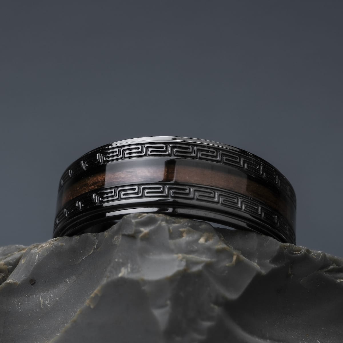 "Numerary Ring", a stylish ring featuring walnut and gray design, with intricate dark patterns.