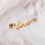 "Love-Charm" charm with gold lettering and pearl accents on a soft background style.