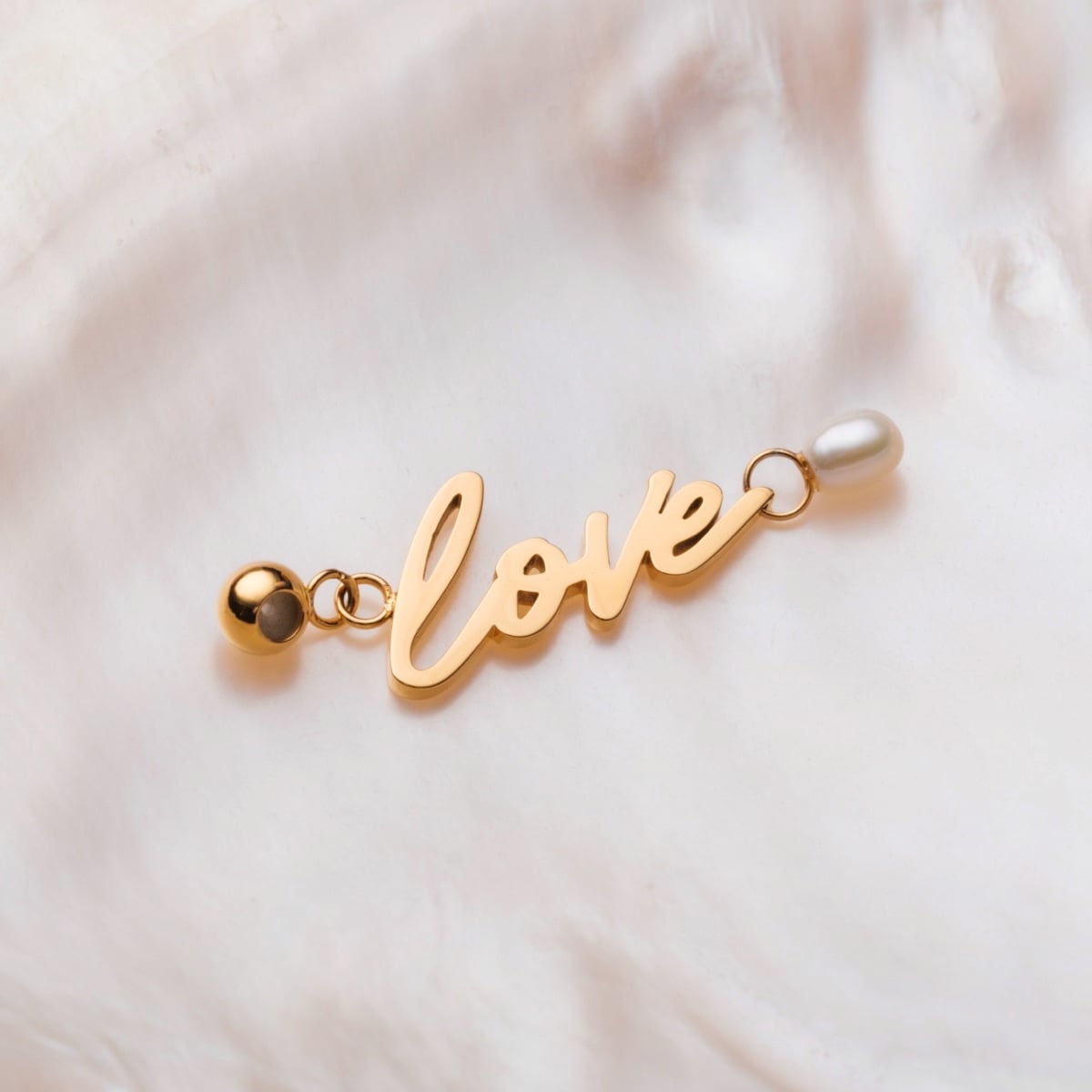 "Love-Charm" charm with gold lettering and pearl accents on a soft background style.