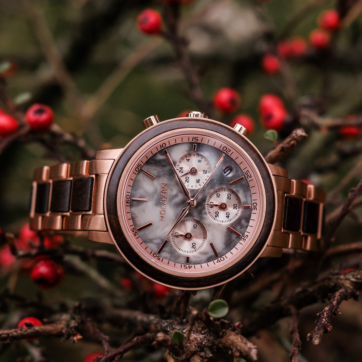 "Calina", elegant wristwatch with maple and marble detailing, set against a natural background with vibrant red accents.