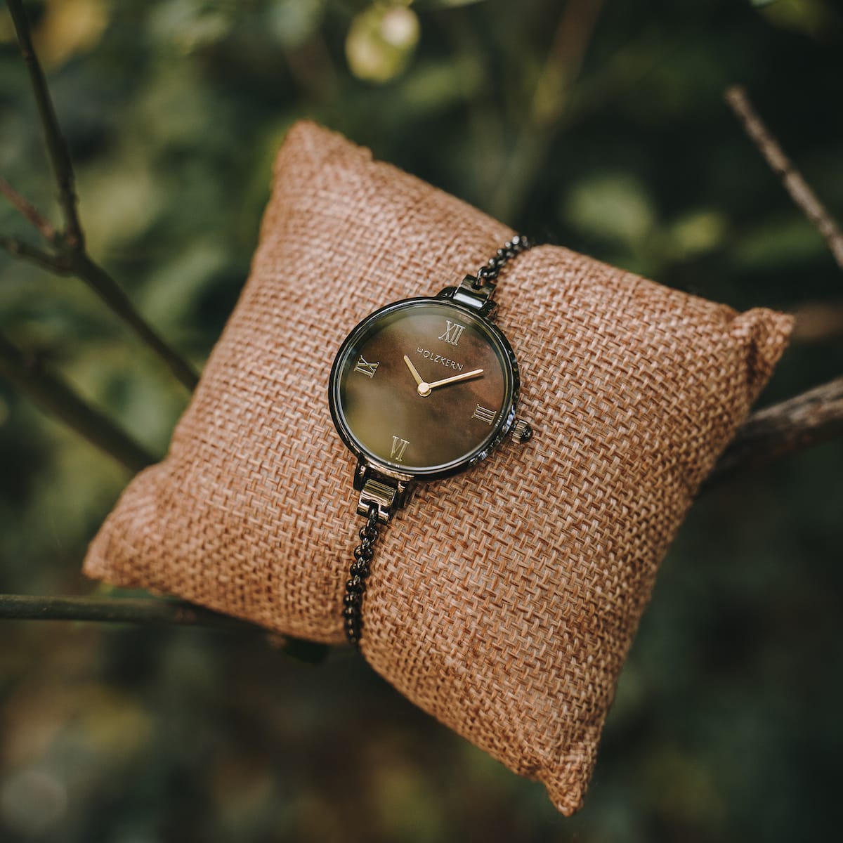 "Élisa" watch featuring a nacre dial and dark gray accents on a rustic burlap pillow.