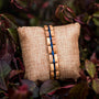 "Fantasia" bracelet crafted with olivewood and blue accents, presented on burlap amidst foliage.