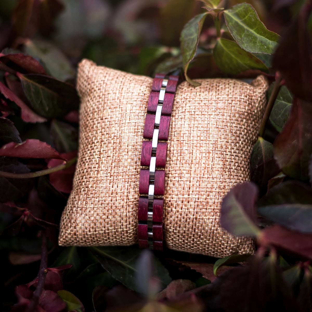 "Fantasia" bracelet with amaranth and silver accents, featuring a woven design against a natural backdrop.
