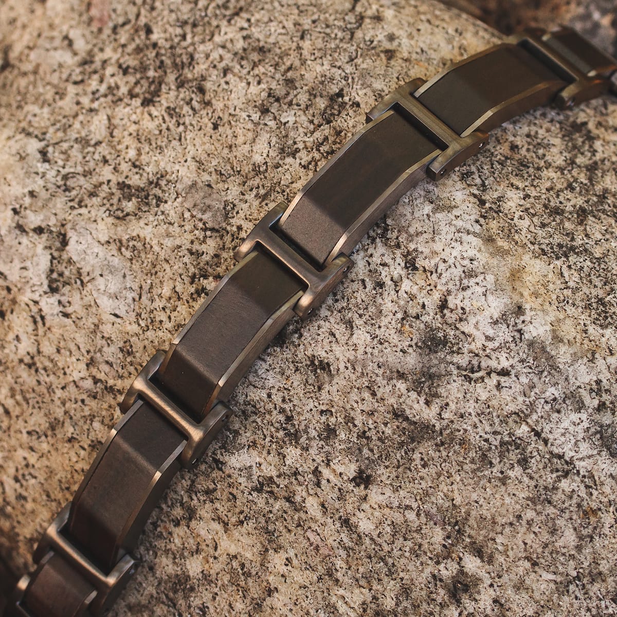 "Acapella" bracelet featuring a sleek Leadwood and Dark Grey design on textured stone background.
