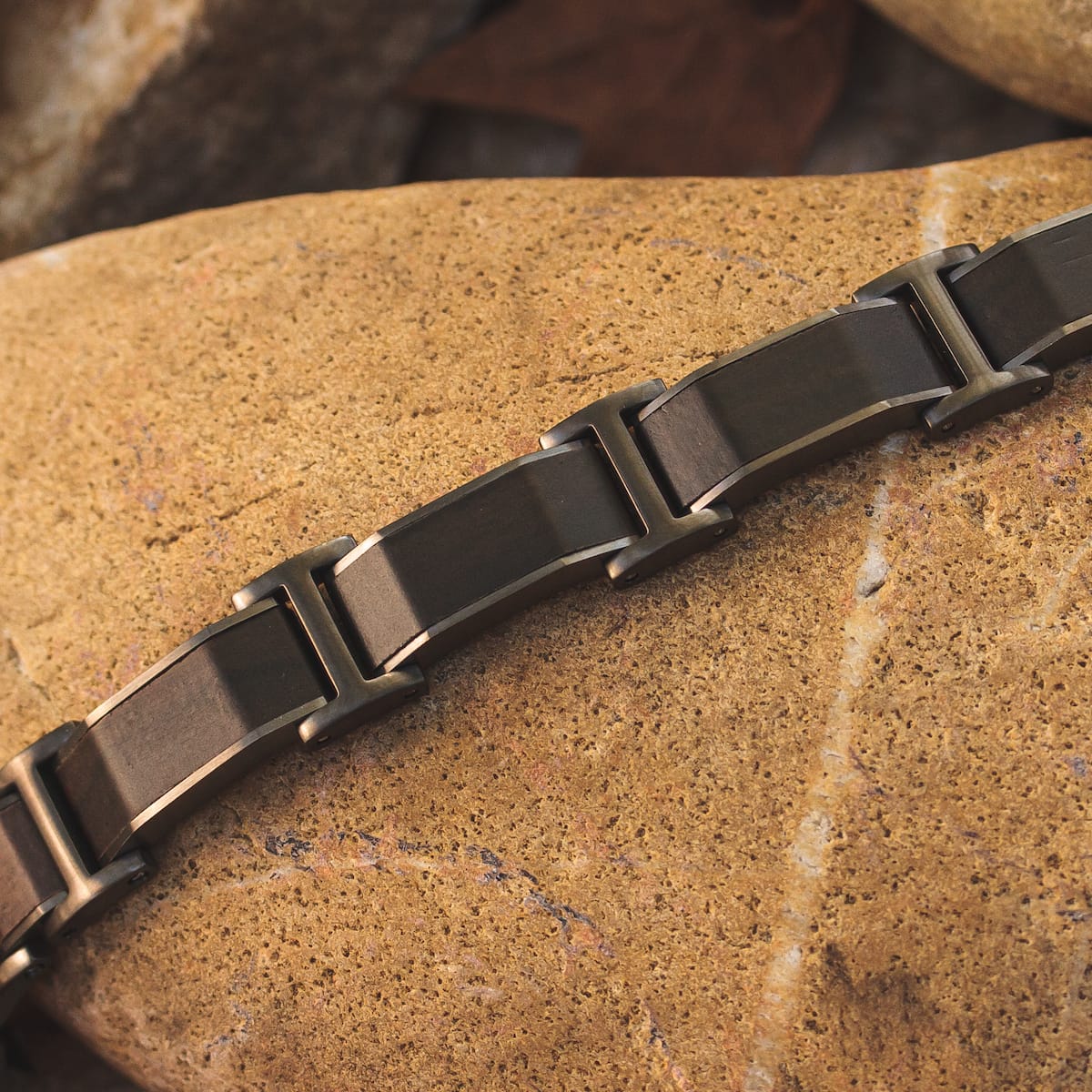 "Acapella", a stylish bracelet featuring Leadwood and dark grey elements, set against a natural stone background.