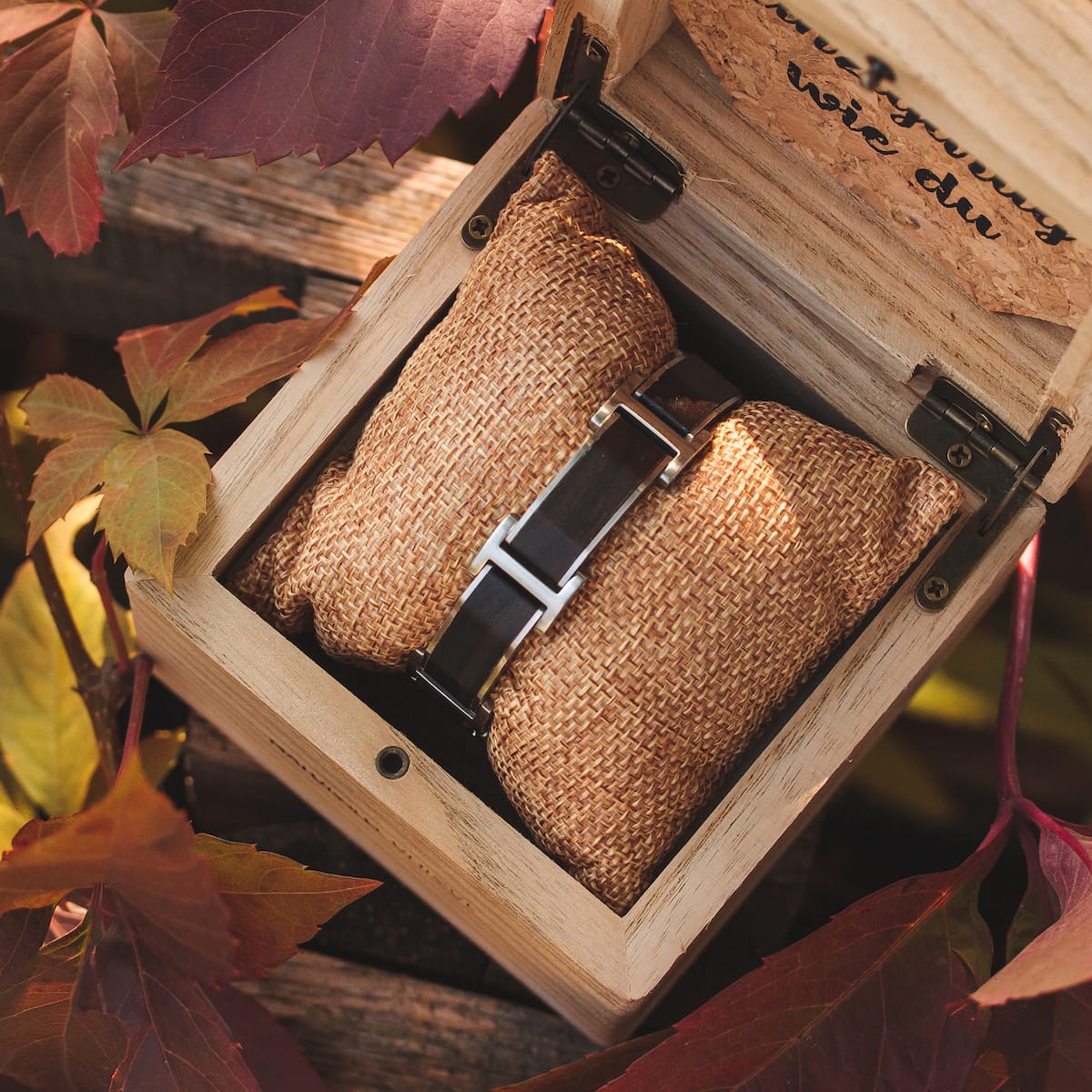 "Acapella" watch, featuring a leadwood and silver design, nestled in a rustic box with autumn leaves.