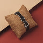 "Acapella" bracelet with Leadwood and Silver accents, elegantly styled on a textured fabric cushion.