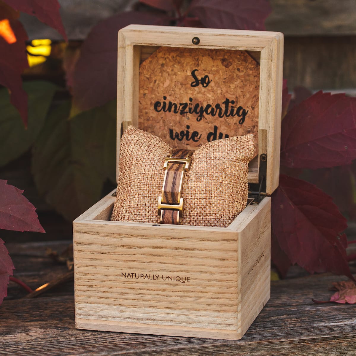 "Acapella" watch, crafted from zebrawood and gold, elegantly displayed in a wooden box with burlap cushion for a rustic touch.