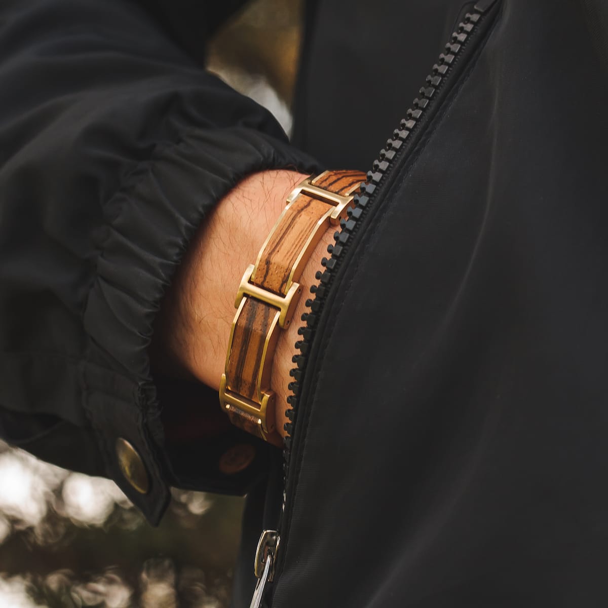 "Acapella" watch featuring a zebrawood and gold design, worn with a black jacket for a stylish contrast.