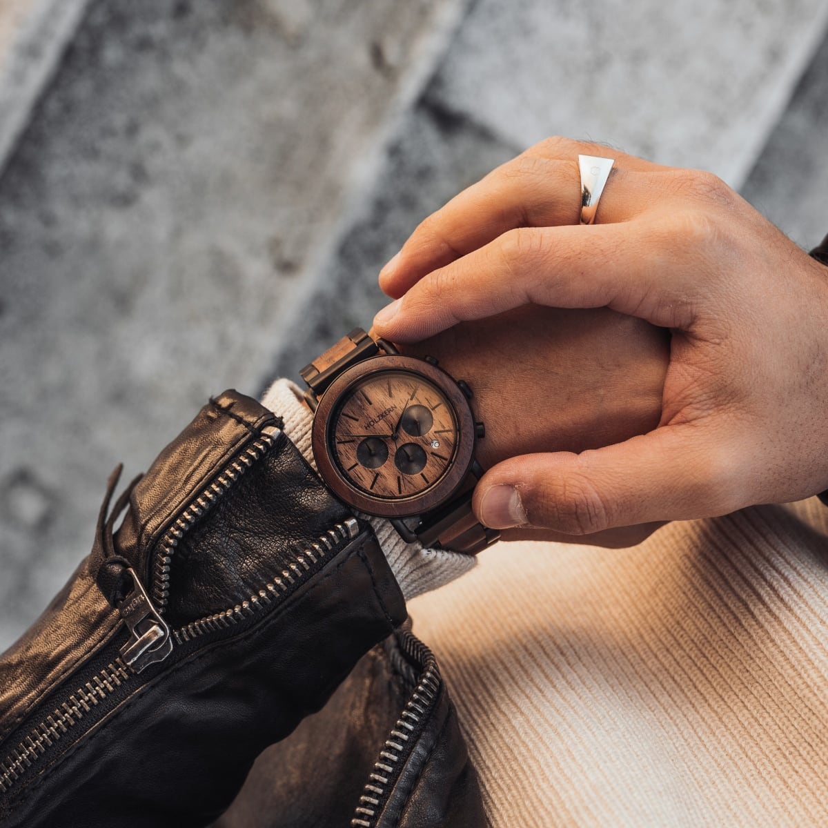 "Dusk" watch, featuring a walnut and black design, hero by a person wearing a leather jacket.