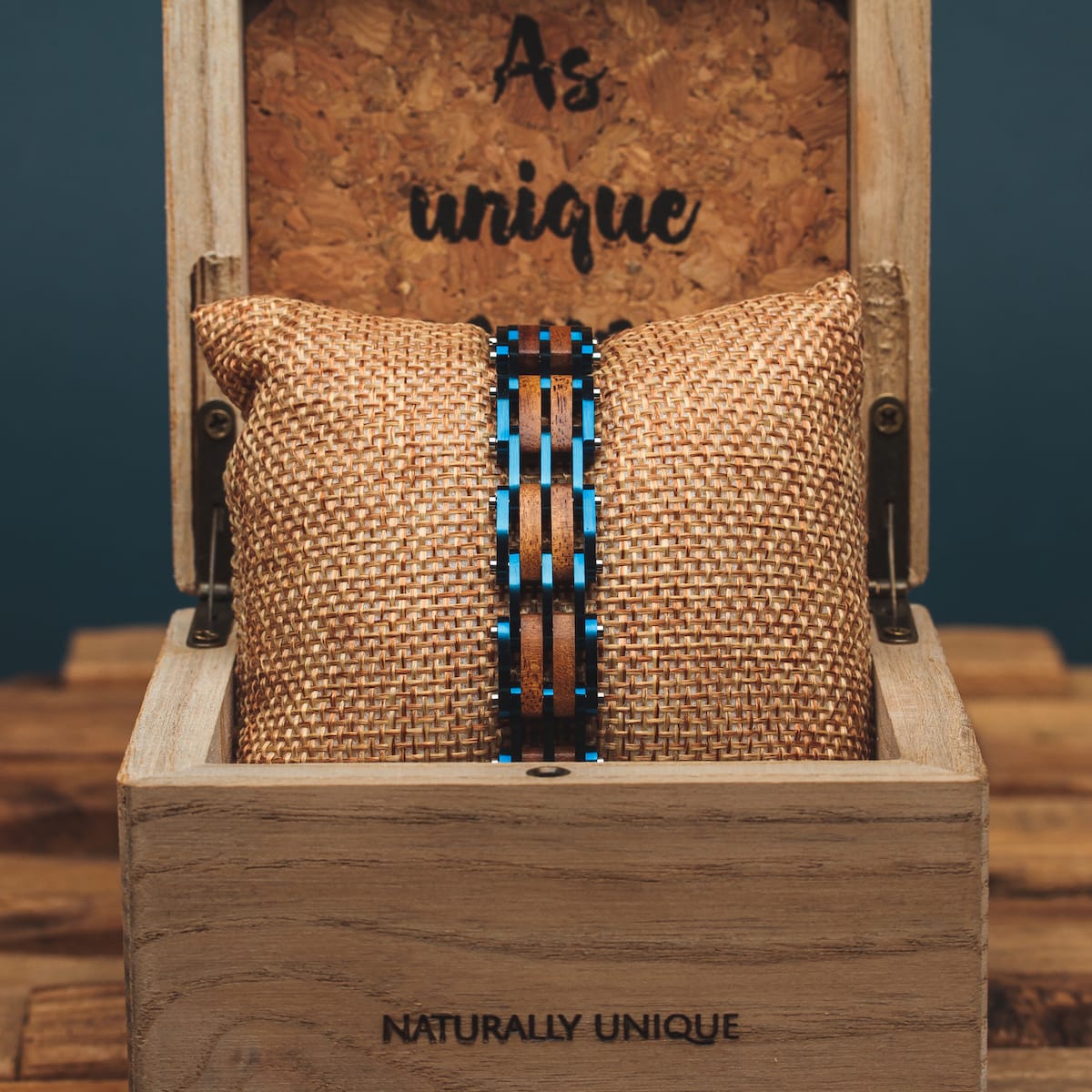 "Adagio" watch, featuring a koa wood and blue accent design, displayed in a rustic wooden box.