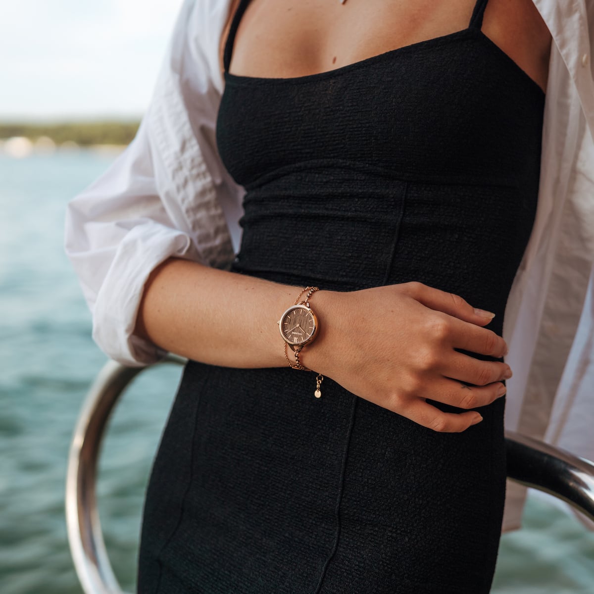 "Blissed" watch with Walnut and Rose Gold finish, worn on a woman's wrist by the water.