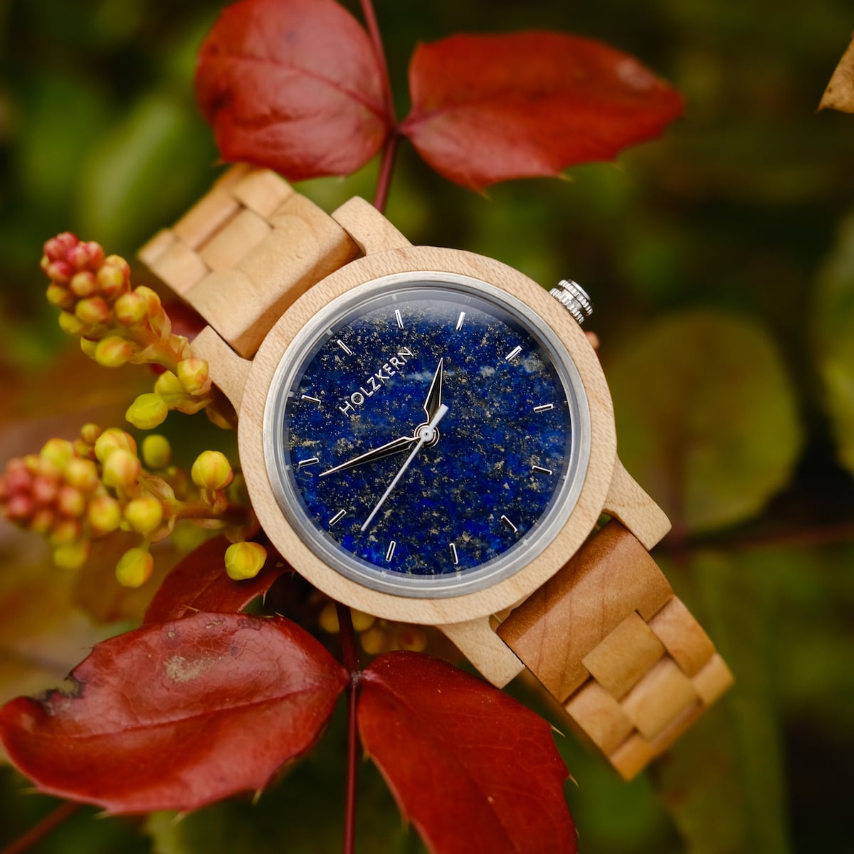 "Water" wooden wristwatch featuring a maple frame and lapis lazuli dial, set against a backdrop of autumn leaves.