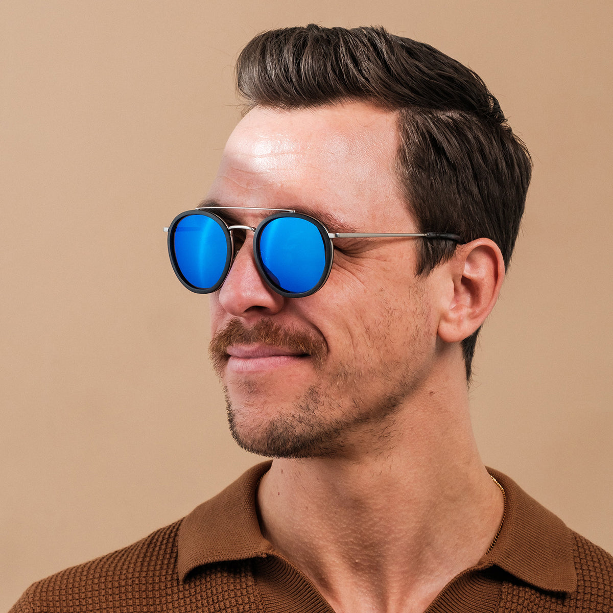 "The Enchanting" sunglasses with round blue lenses and antique silver frame exuding a sleek, modern style.