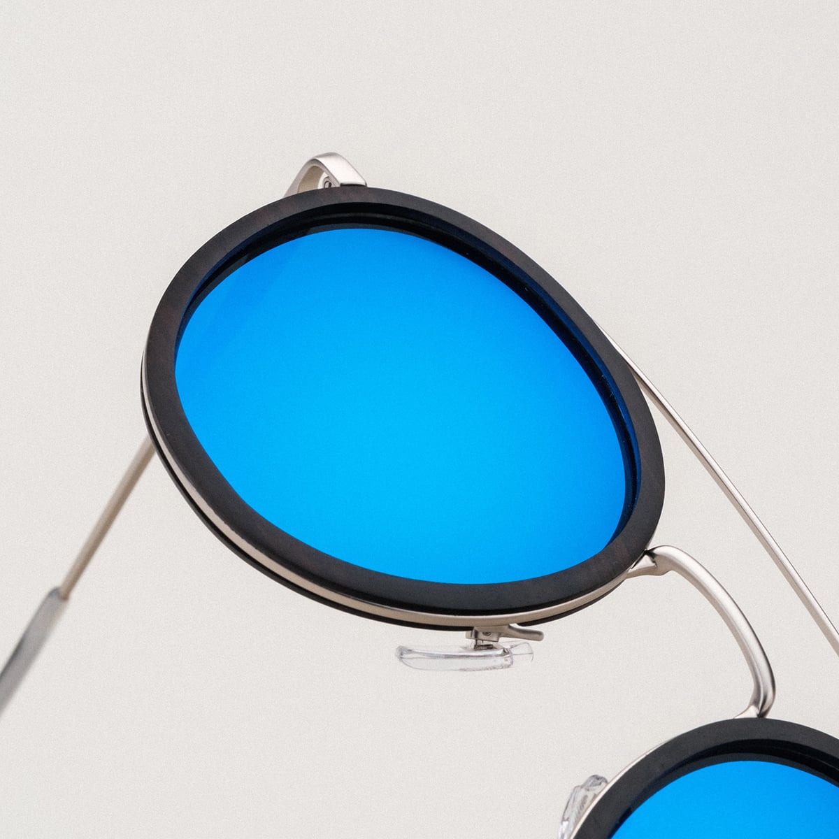 "The Enchanting" sunglasses with blue lenses, sleek leadwood frame, and antique silver details.