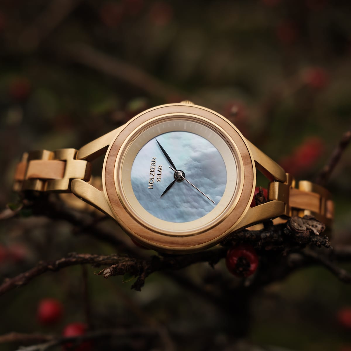 "Tumi" watch featuring an elegant olive and nacre design with a luxurious gold-toned metal band.