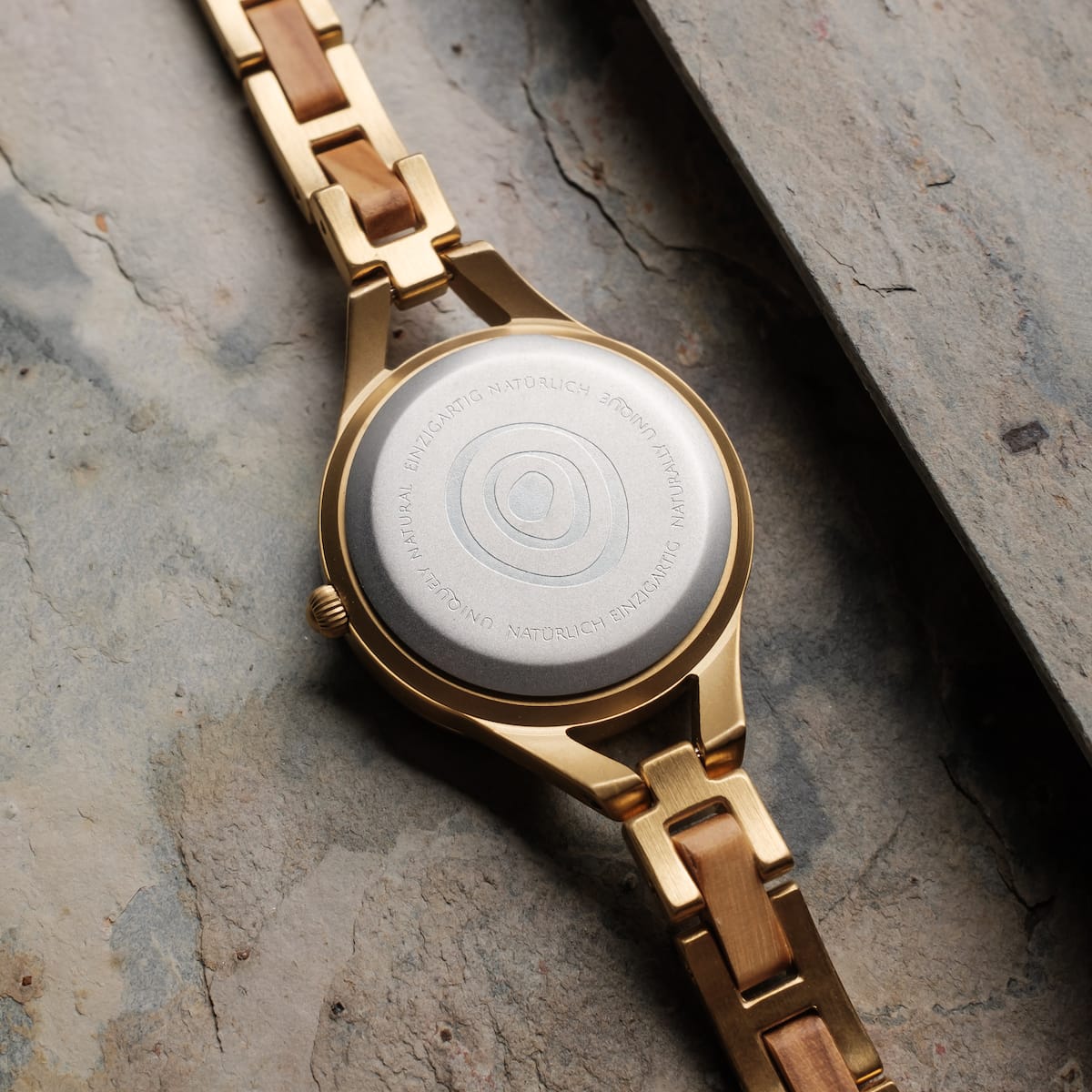 "Tumi", a stylish watch with an elegant olive and nacre design, featuring a unique metallic back.