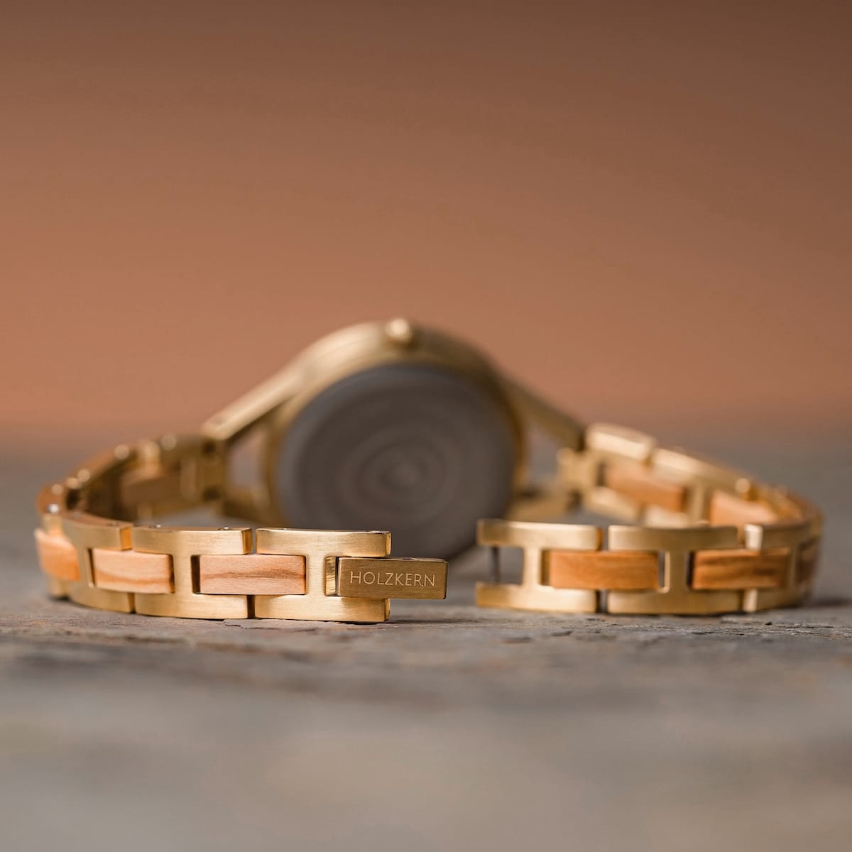 "Tumi" watch with olive-toned metal links and nacre inlays.