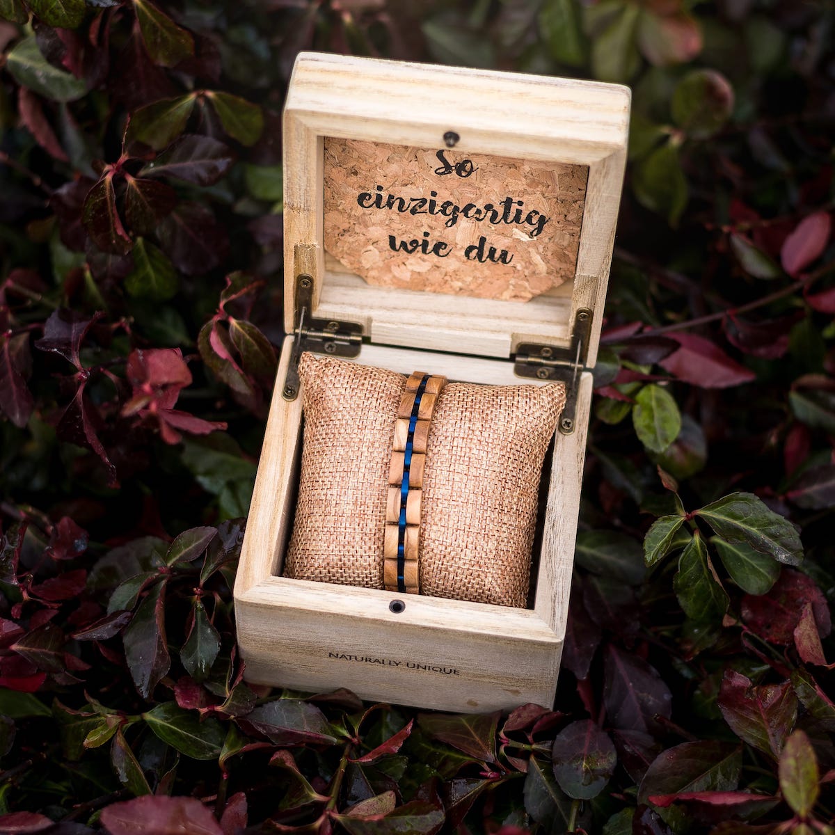 "Fantasia" bracelet features an olivewood and blue design in a rustic, cushioned wooden box.
