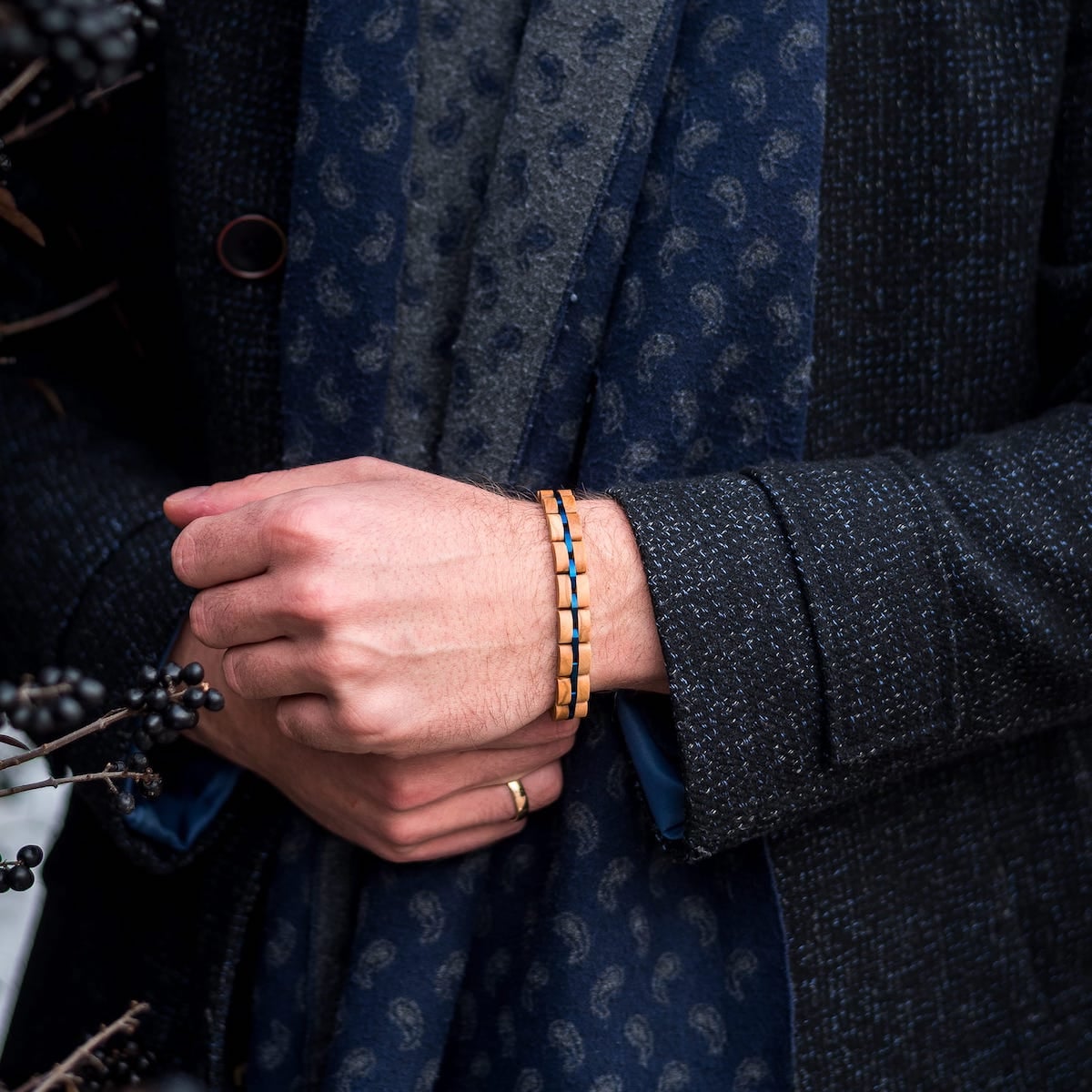"Fantasia" bracelet featuring a stylish olivewood and blue design on a wrist against a textured dark jacket background.