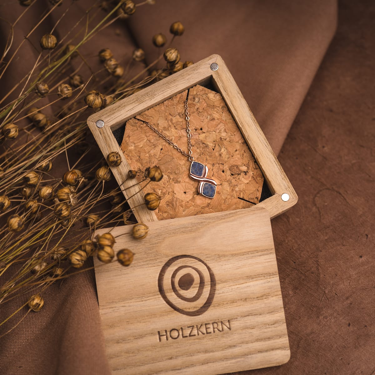 "Mosaic Necklace" necklace with lapis lazuli and rose gold accents, displayed in a rustic wooden box.