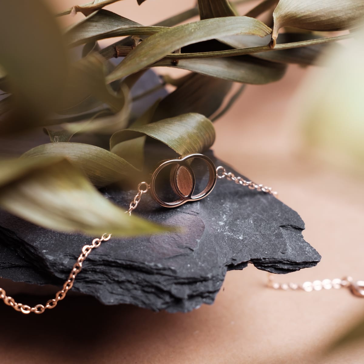 "Effigy Bracelet", a stylish bracelet in walnut and rose gold, elegantly displayed on a natural slate background.