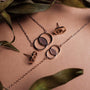 Effigy earrings with a walnut and rose gold design displayed on a brown background.