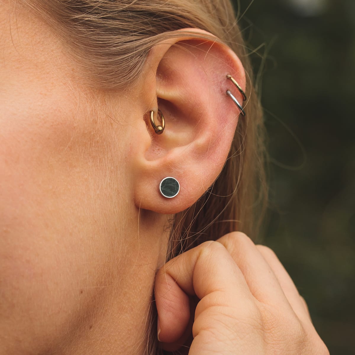 "Concentric earrings" stud earrings, minimalist marble with silver accents, worn stylishly on ear.