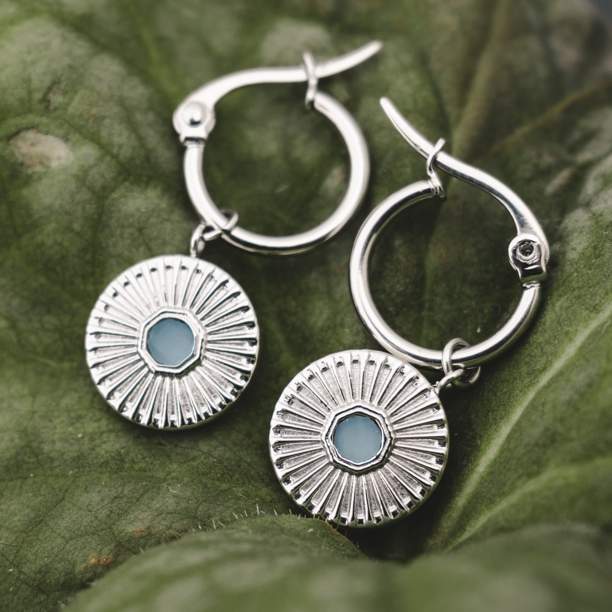 "Stencil Earrings": Elegant silver hoop earrings featuring aquamarine-inspired accents with a radiant, textured design.
