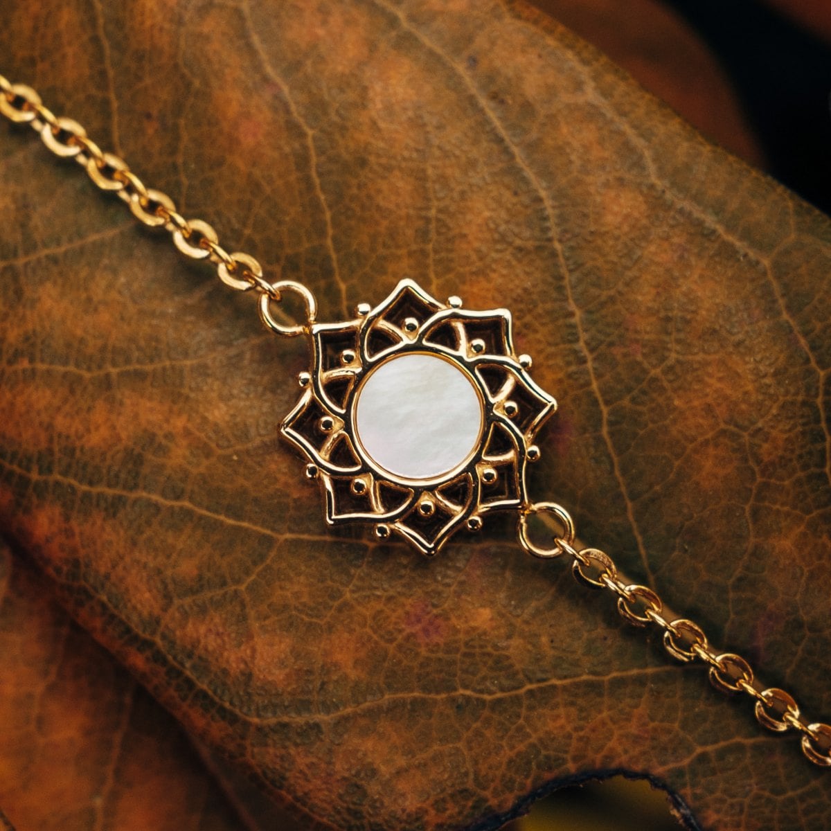 "Composition Bracelet" bracelet featuring a white nacre center with gold detailing, showcasing an elegant ornate design.