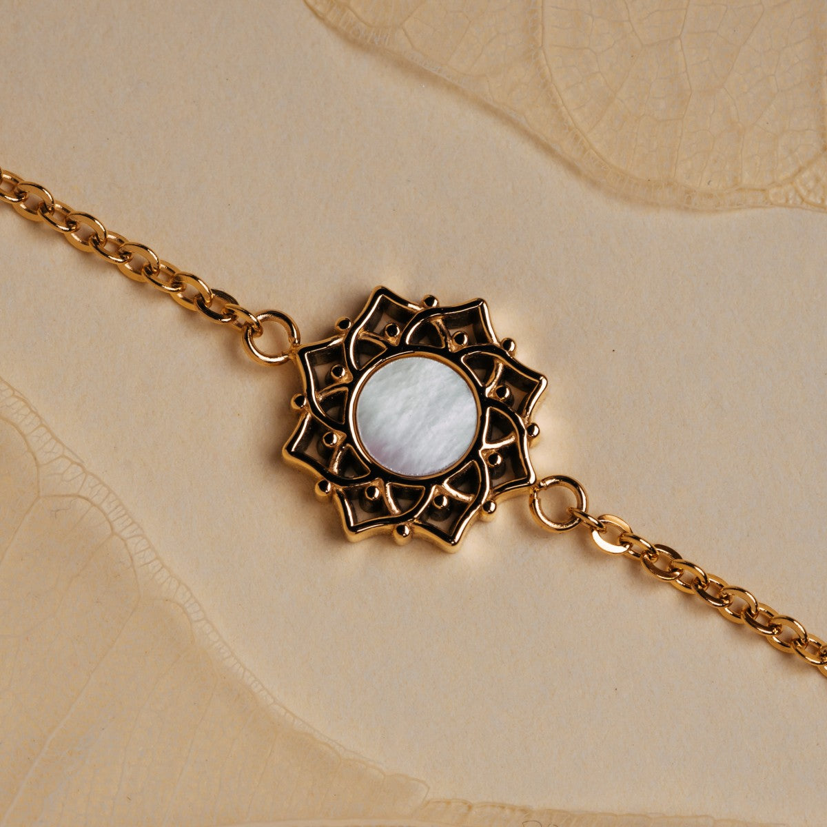 "Composition Bracelet", a gold bracelet with white nacre detail and intricate design.