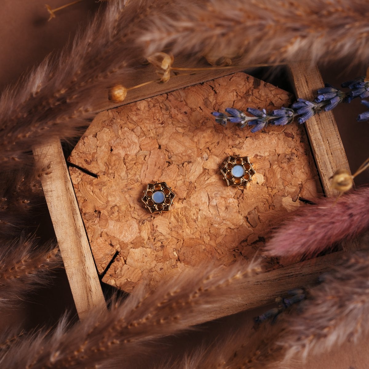 "Composition Earrings", elegant earrings with a blue nacre and gold design, styled amidst natural decor.