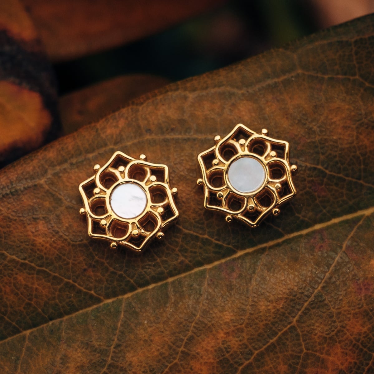 "Composition Earrings" earrings featuring white nacre and gold in an intricate floral design.