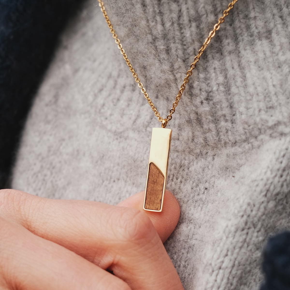 "Ephemera Necklace" necklace, gold chain with rectangular koa wood and gold pendant, styled on gray knit.