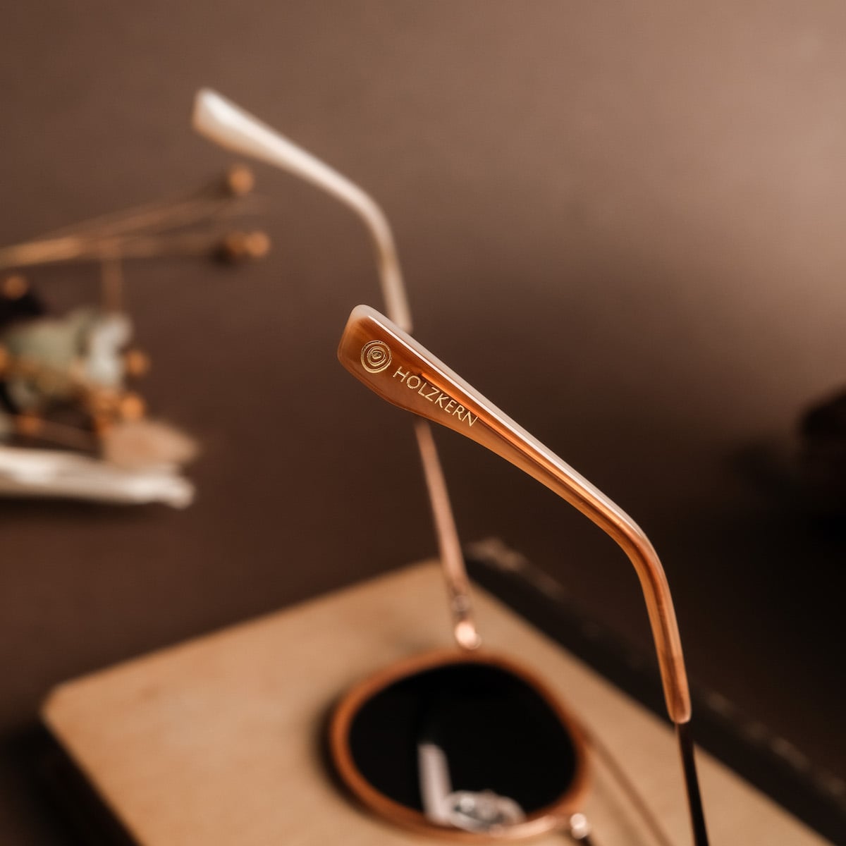 "The Enchanting" eyewear, featuring a sophisticated cinnamon wood and matte gold design with a modern aesthetic.