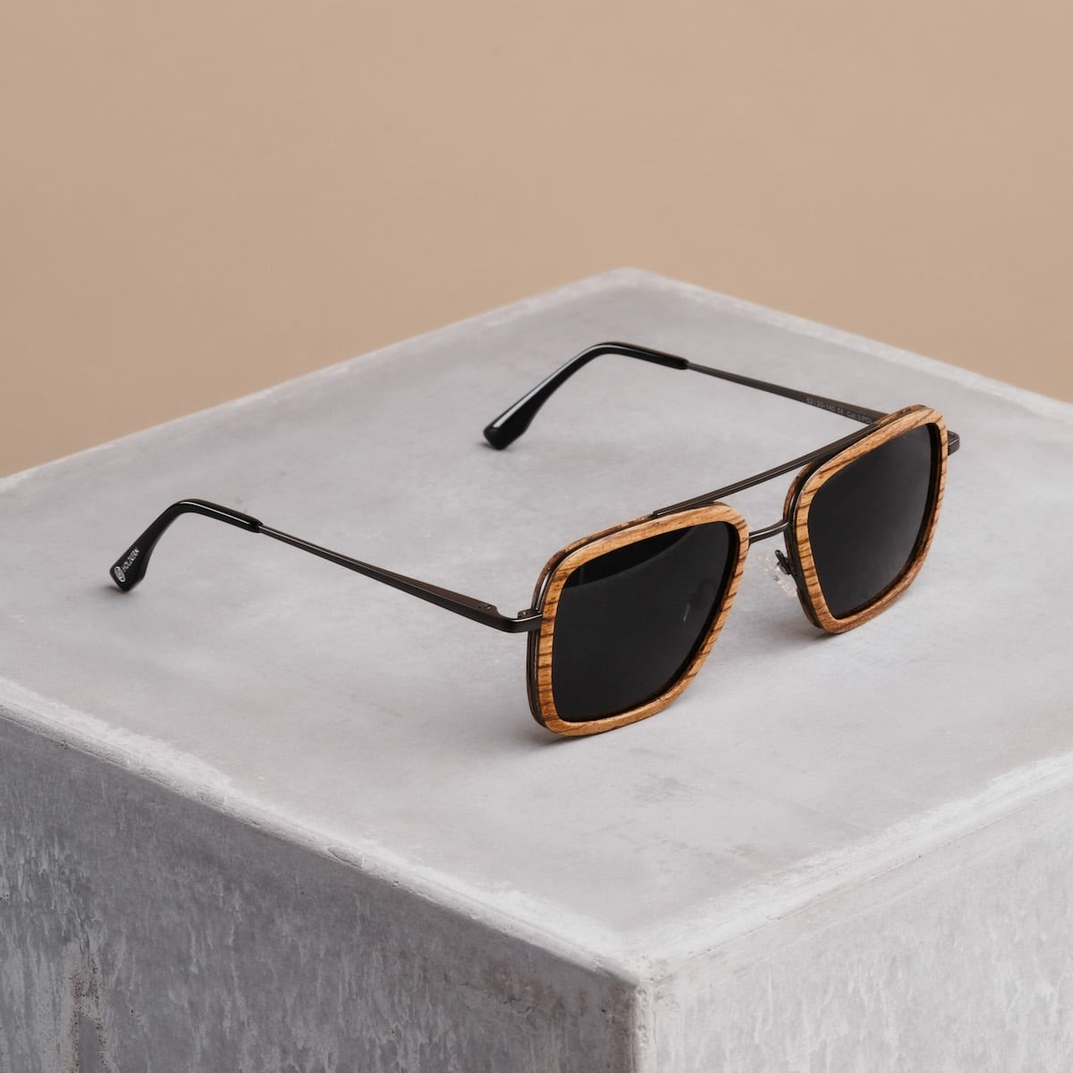 "The Logician" sunglasses featuring a zebrawood frame and dark grey lenses on a concrete surface.