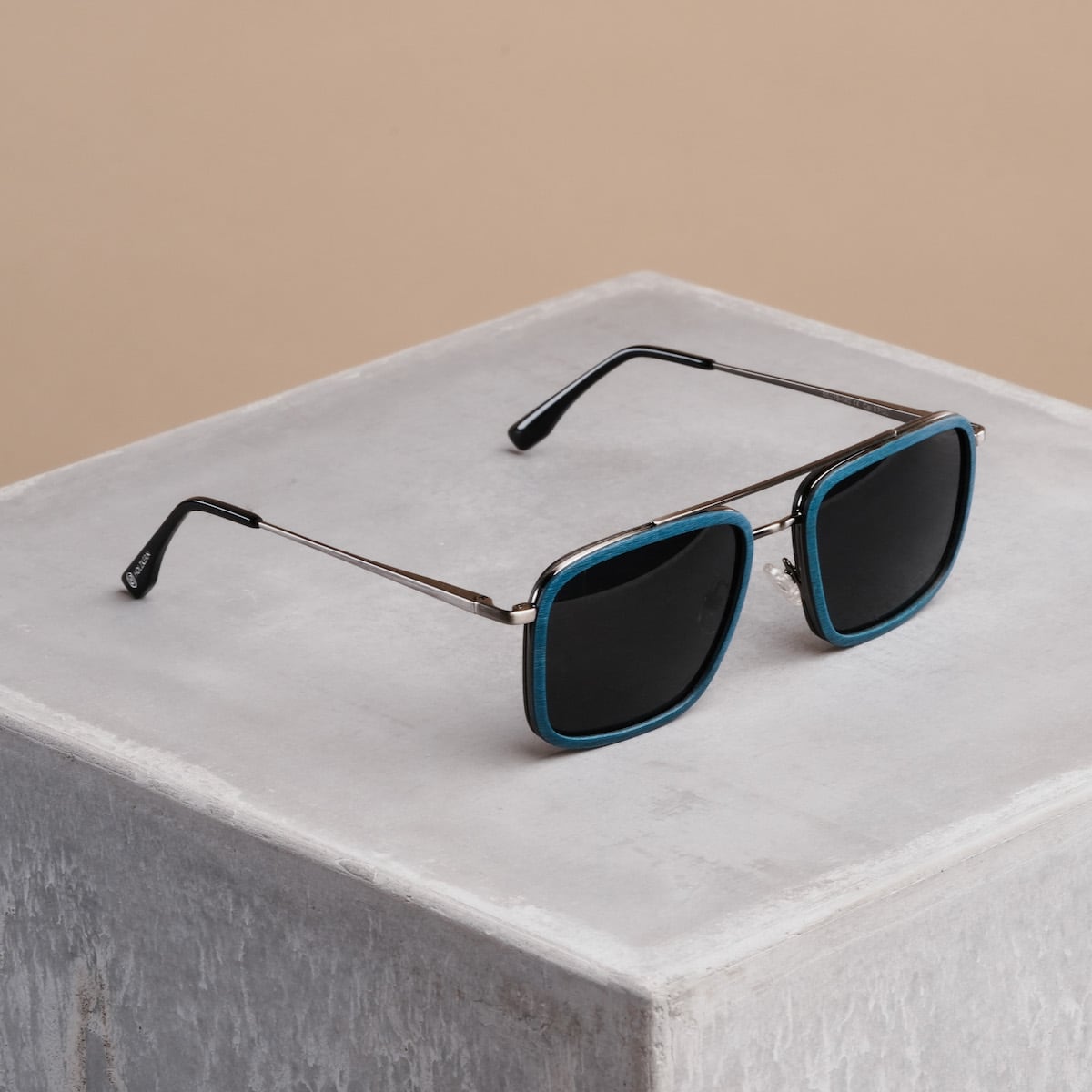 "The Prominent" sunglasses with a maple and dark grey finish, featuring a sleek, modern design on a minimalist stand.