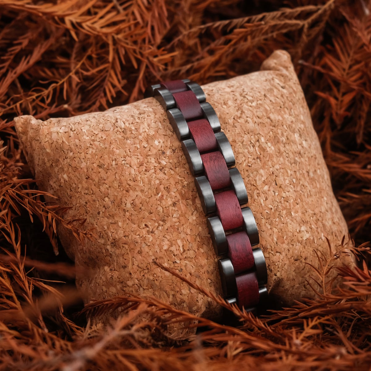 "Triad" bracelet, featuring amaranth and gray materials, showcased on a natural cork display for an earthy aesthetic.