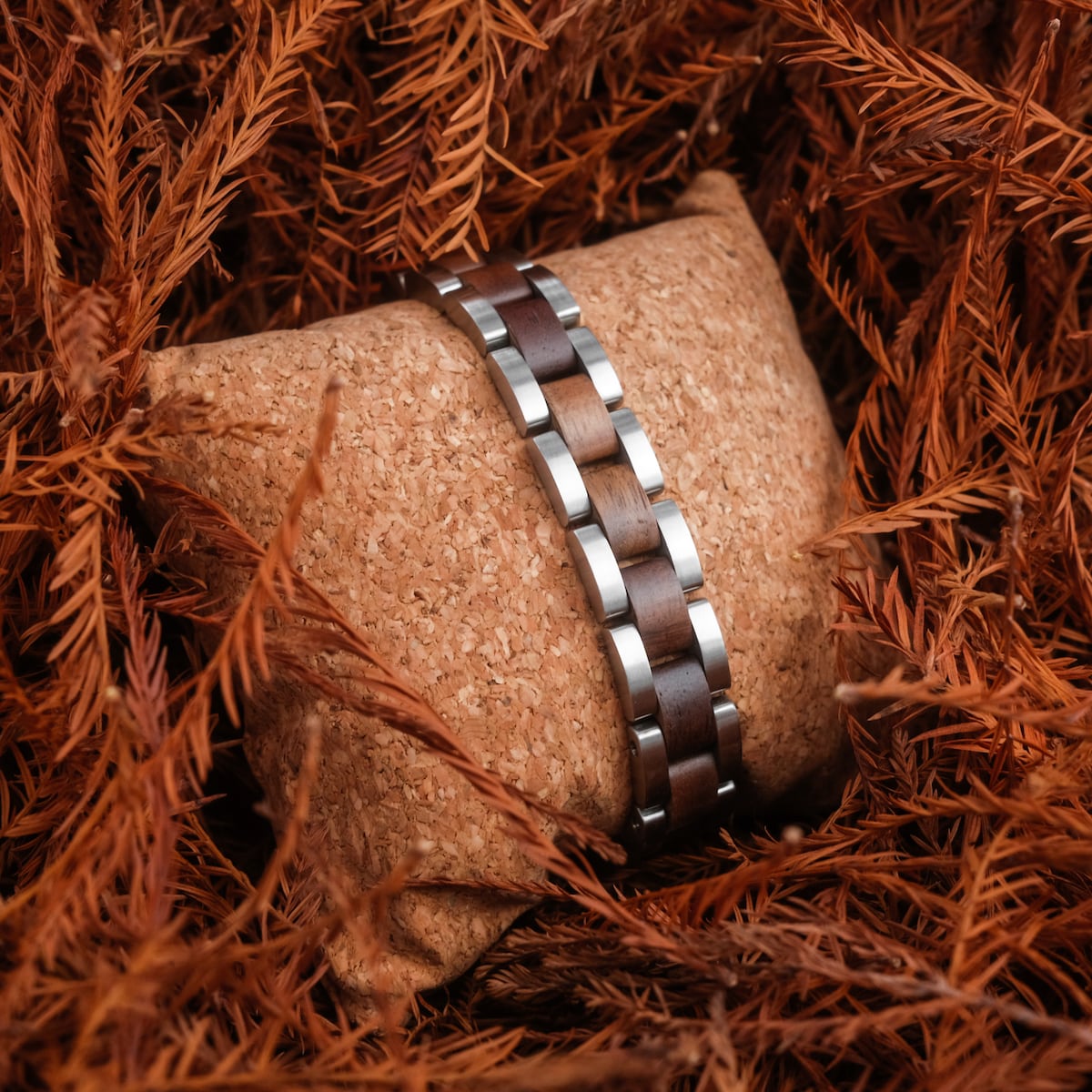 "Triad" bracelet, crafted in walnut and silver, showcasing a sleek and natural design on a textured background.